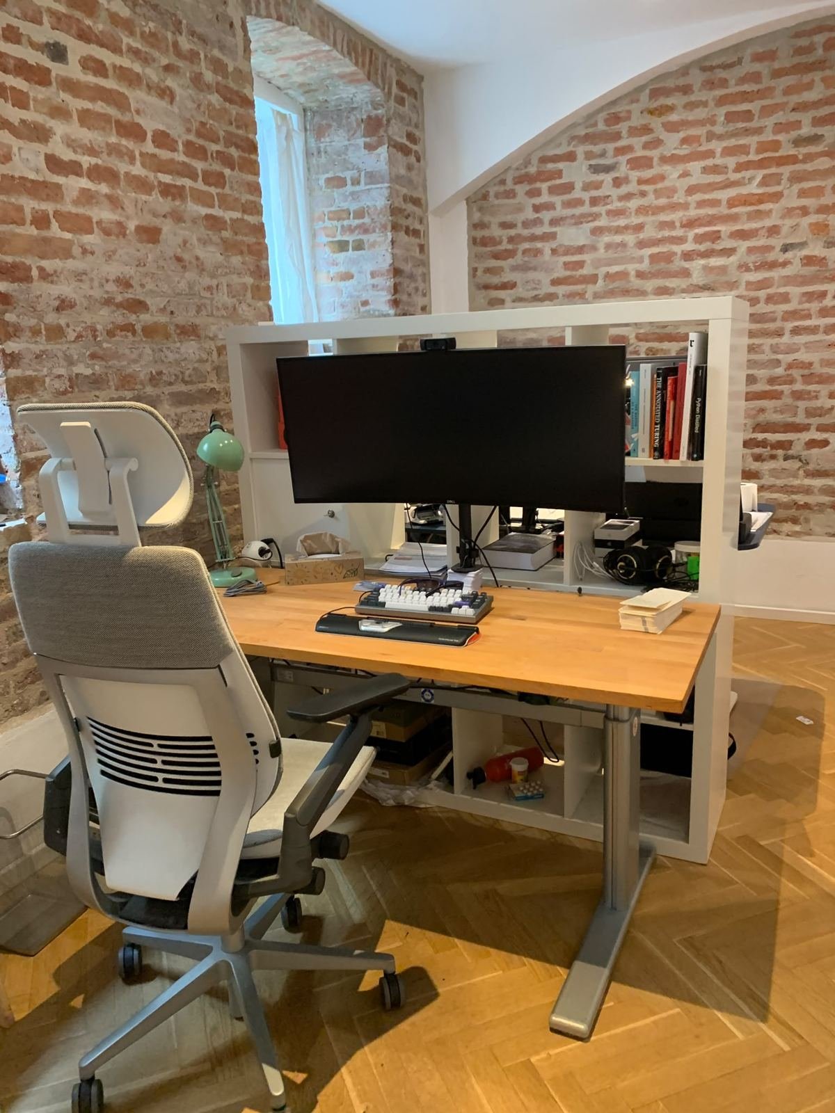 Dedicated Desk mit Monitor vor Ziegelwand